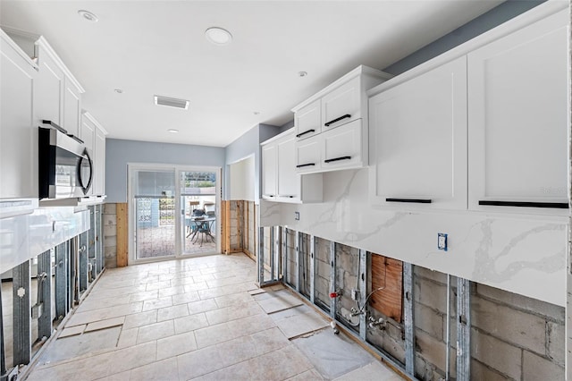 kitchen with white cabinetry and light stone countertops