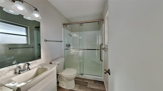 bathroom featuring hardwood / wood-style floors, vanity, toilet, and a shower with shower door