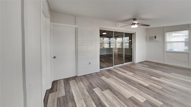 unfurnished bedroom featuring an AC wall unit, ceiling fan, and light wood-type flooring