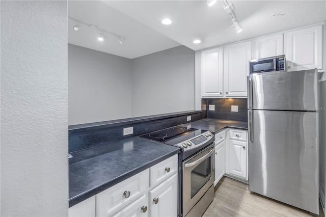 501 Knights Run Ave Unit 2308, Tampa, FL 33602 - kitchen with rail lighting, tasteful backsplash, stainless steel appliances, white cabinets, and light hardwood / wood-style floors