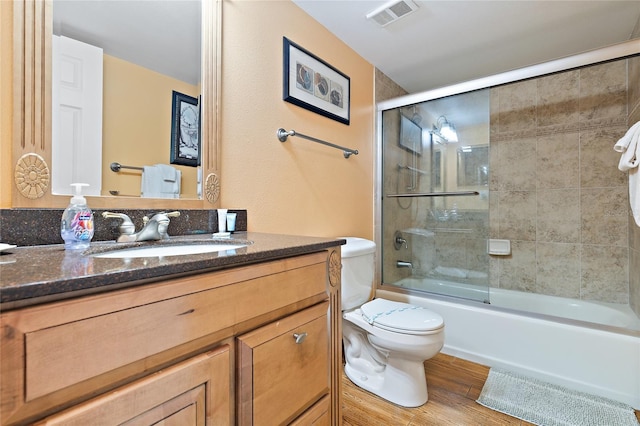 full bathroom featuring combined bath / shower with glass door, hardwood / wood-style floors, vanity, and toilet