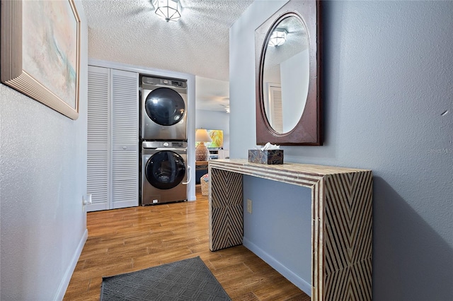 washroom with stacked washer and dryer, hardwood / wood-style floors, and a textured ceiling