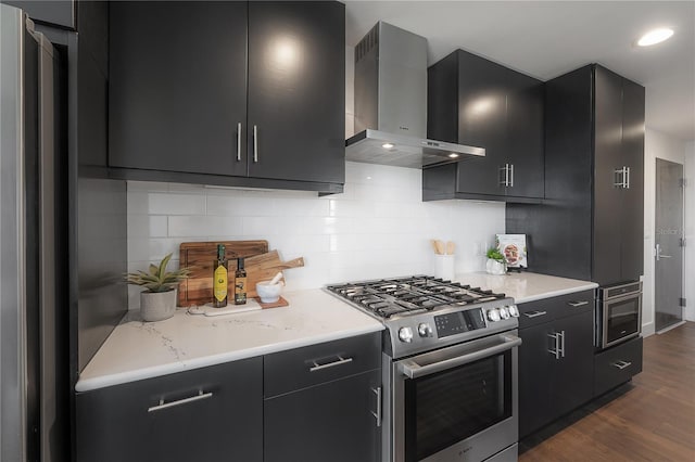 kitchen featuring wall chimney exhaust hood, dark hardwood / wood-style floors, stainless steel stove, and tasteful backsplash