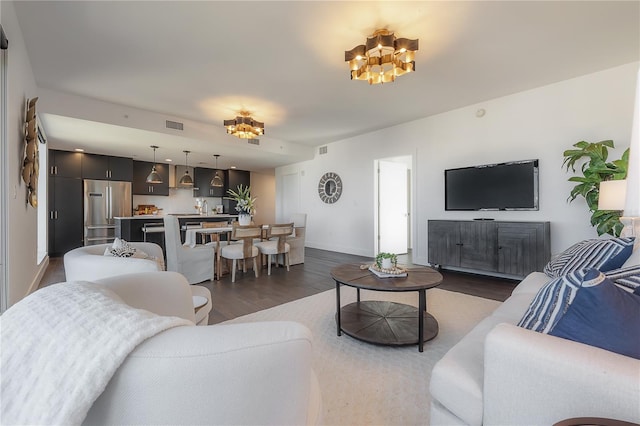 living room featuring a chandelier and dark wood-type flooring