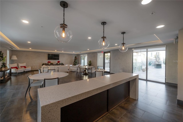 kitchen featuring a tray ceiling, light stone counters, and hanging light fixtures