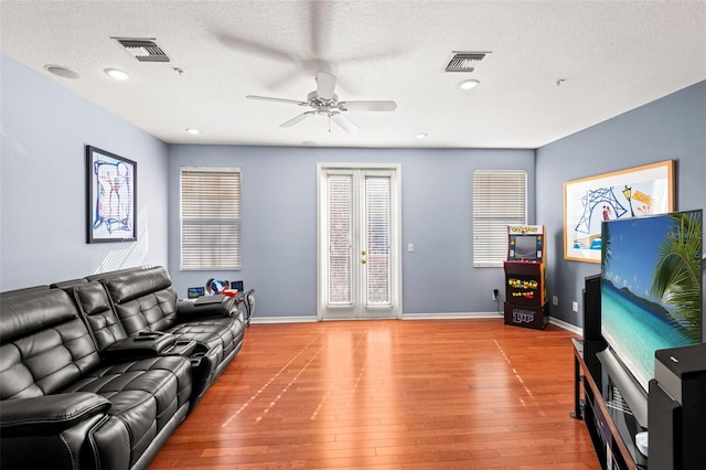 living room with french doors, a textured ceiling, hardwood / wood-style floors, and ceiling fan