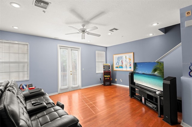 living room with a textured ceiling, ceiling fan, french doors, and wood-type flooring