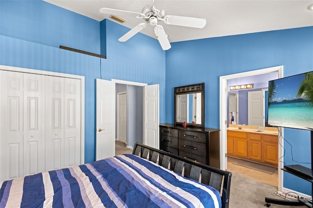 bedroom with ensuite bathroom, a closet, ceiling fan, and light colored carpet