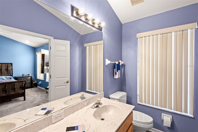 bathroom with toilet, vaulted ceiling, and vanity