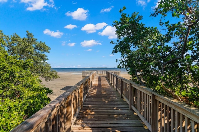 view of dock featuring a beach view and a water view