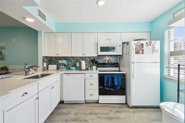 kitchen with white appliances, backsplash, sink, light hardwood / wood-style floors, and white cabinetry