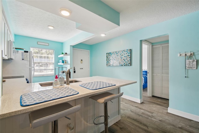 kitchen with a textured ceiling, white cabinets, dark hardwood / wood-style floors, and white refrigerator