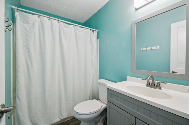 bathroom featuring vanity, a textured ceiling, toilet, and walk in shower