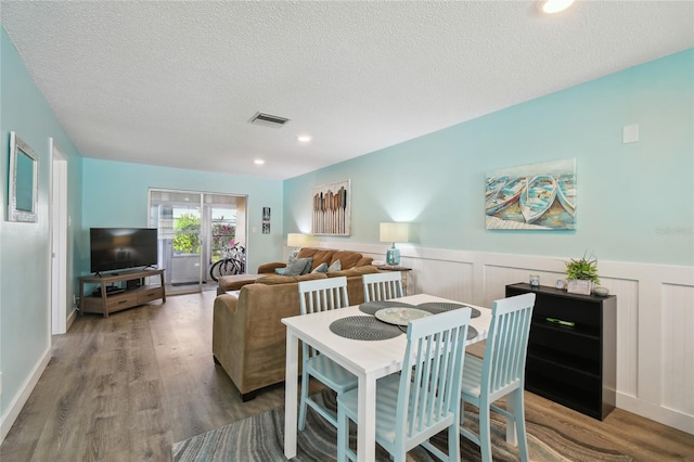 dining room with hardwood / wood-style floors and a textured ceiling