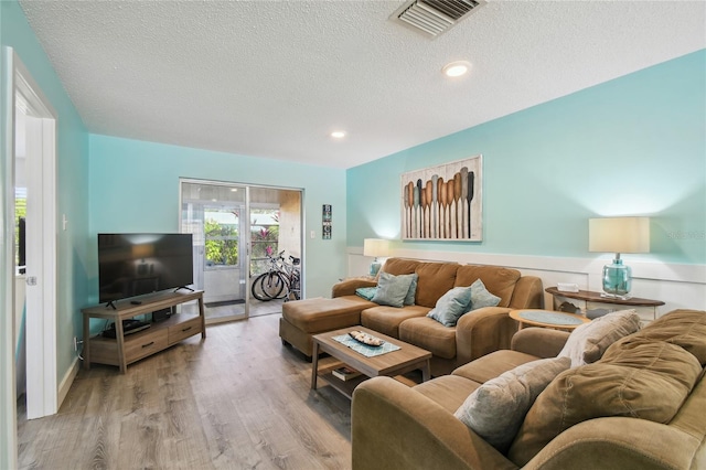 living room with light hardwood / wood-style floors and a textured ceiling