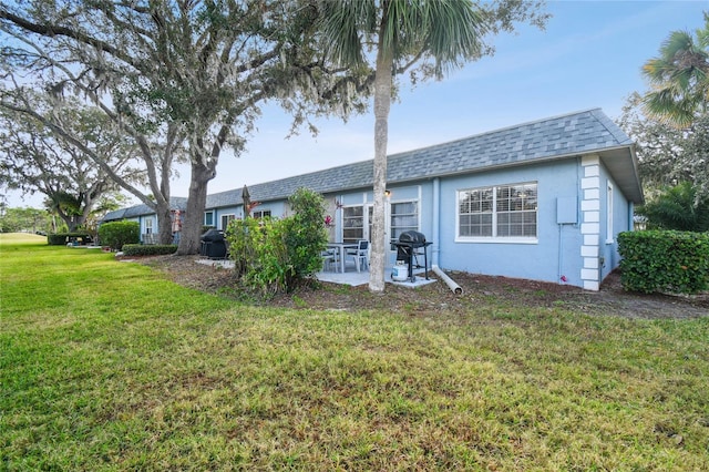 back of house with a yard and a patio