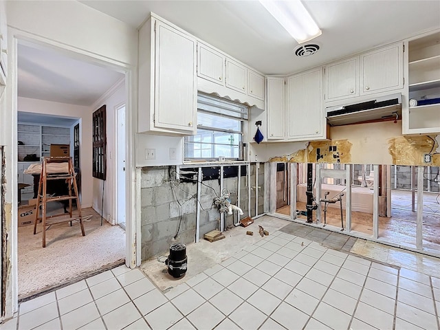 kitchen with light colored carpet, white cabinetry, and ornamental molding