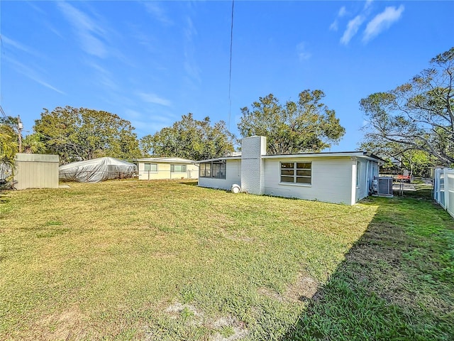 rear view of property featuring a yard and central AC unit