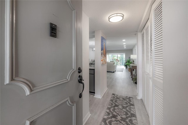 hall with a textured ceiling and light hardwood / wood-style flooring