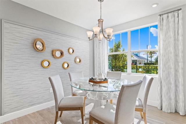 dining area with light hardwood / wood-style flooring and an inviting chandelier