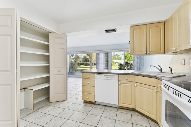 kitchen with light tile patterned floors, white appliances, sink, and light brown cabinetry