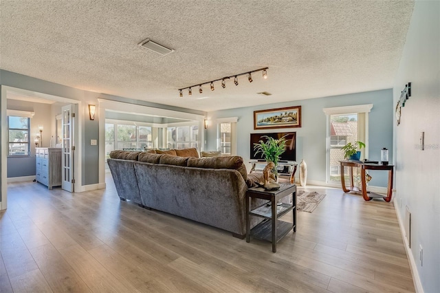 living room with plenty of natural light, light hardwood / wood-style floors, and a textured ceiling