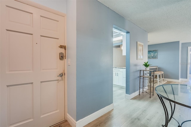 hallway with light wood-type flooring and a textured ceiling