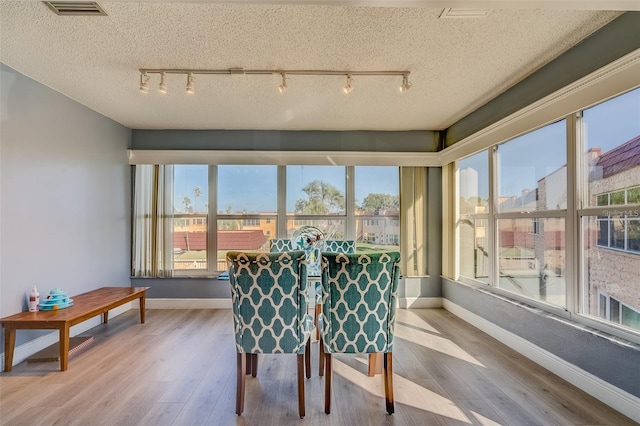 dining room with a textured ceiling, light wood-type flooring, and rail lighting