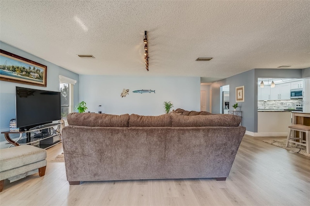 living room with track lighting, a textured ceiling, and light wood-type flooring