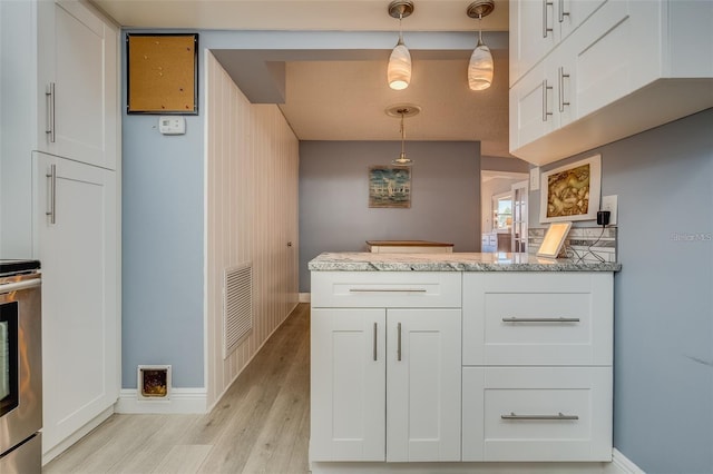 kitchen with white cabinetry, light hardwood / wood-style flooring, hanging light fixtures, and light stone counters