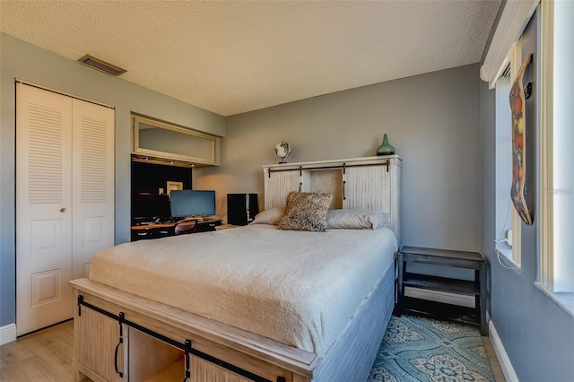 bedroom featuring a closet, a textured ceiling, and light hardwood / wood-style flooring