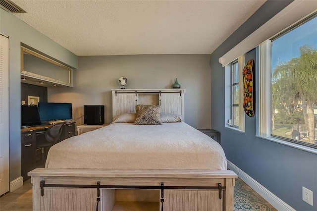 bedroom with light hardwood / wood-style flooring and a textured ceiling