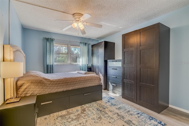 bedroom featuring ceiling fan, light hardwood / wood-style floors, and a textured ceiling