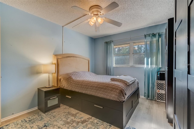 bedroom with a textured ceiling, light hardwood / wood-style flooring, and ceiling fan