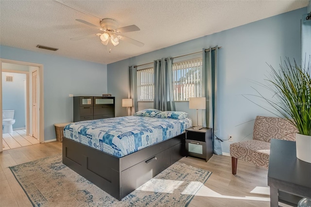 bedroom with ensuite bathroom, ceiling fan, a textured ceiling, and light wood-type flooring