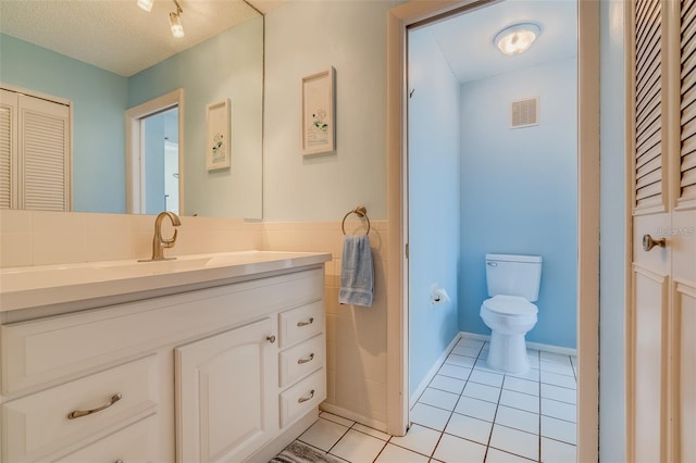 bathroom with tile patterned floors, vanity, toilet, and a textured ceiling