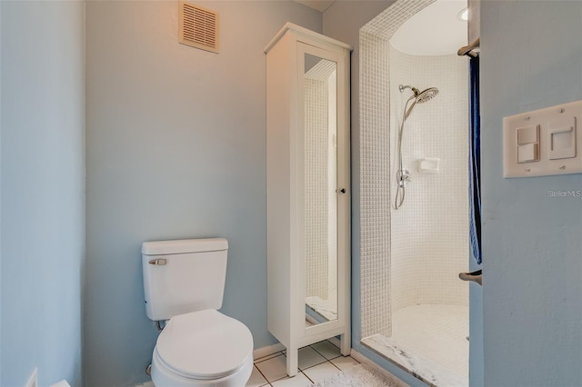 bathroom featuring tiled shower, tile patterned floors, and toilet