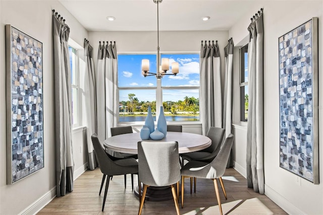 dining room with a notable chandelier, a water view, and light wood-type flooring