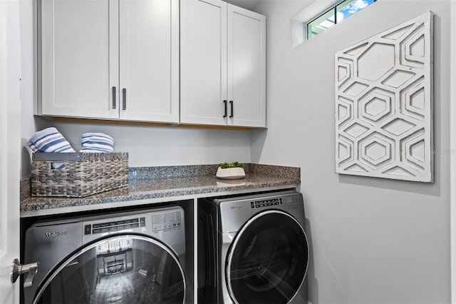 washroom with washing machine and clothes dryer and cabinets