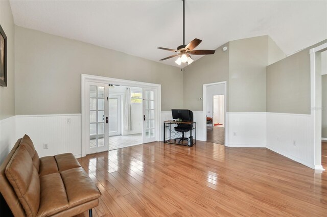 living room with ceiling fan, vaulted ceiling, light wood-type flooring, and french doors