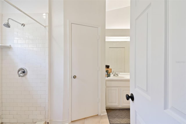 bathroom with tile patterned flooring, vanity, and a tile shower