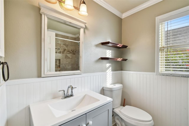 bathroom with tiled shower, crown molding, vanity, and toilet