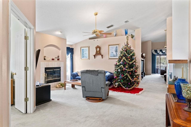 living room featuring ceiling fan, lofted ceiling, light carpet, and a tiled fireplace