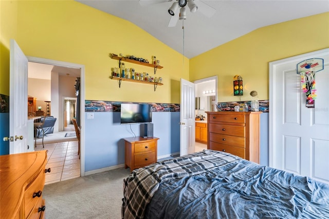 bedroom with ceiling fan, vaulted ceiling, light colored carpet, and ensuite bath