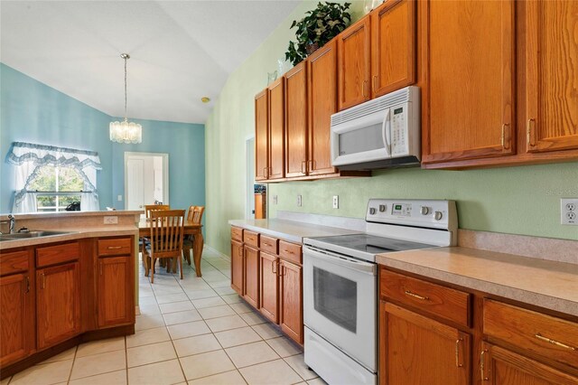 kitchen featuring white appliances, vaulted ceiling, sink, decorative light fixtures, and an inviting chandelier