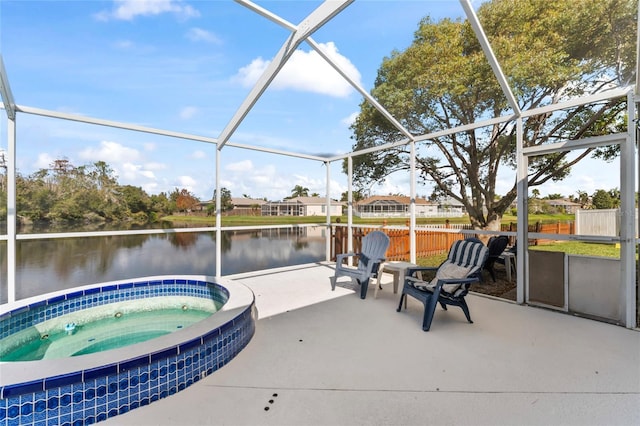 view of pool with an in ground hot tub, a water view, glass enclosure, and a patio area