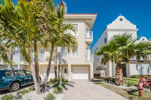 view of front of home featuring decorative driveway, an attached garage, and stucco siding