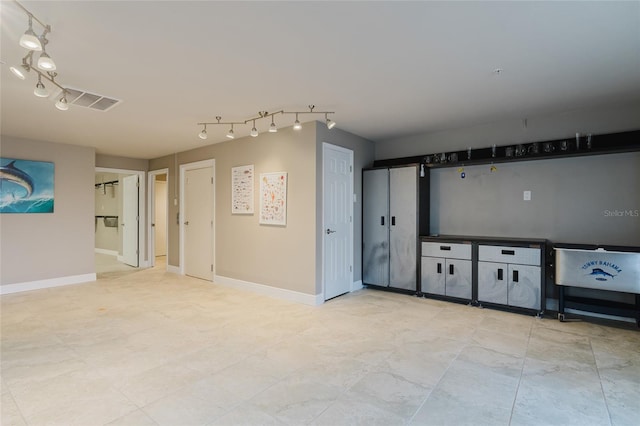 spare room with track lighting, visible vents, and baseboards