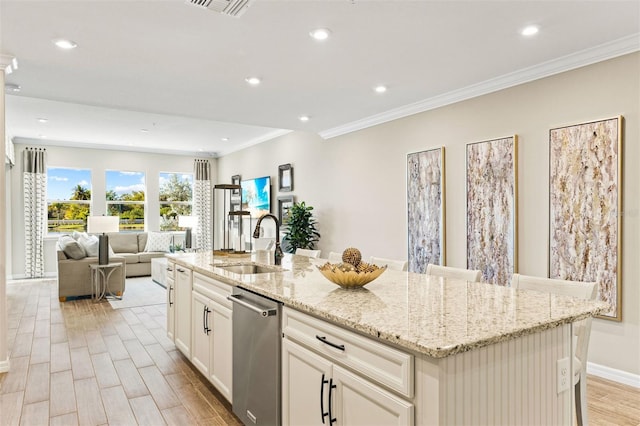 kitchen featuring a breakfast bar area, a center island with sink, stainless steel dishwasher, and sink