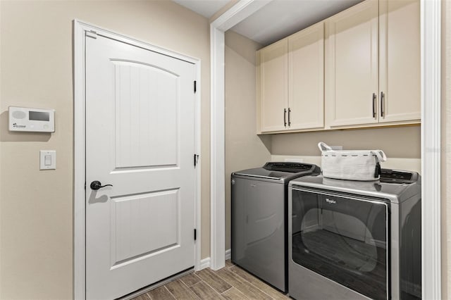 clothes washing area featuring cabinets, separate washer and dryer, and light wood-type flooring